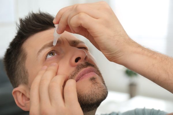 moški uporablja kapljice za oči, ki pomagajo pri suhih očeh, ko je prisotno tudi vnetje vek